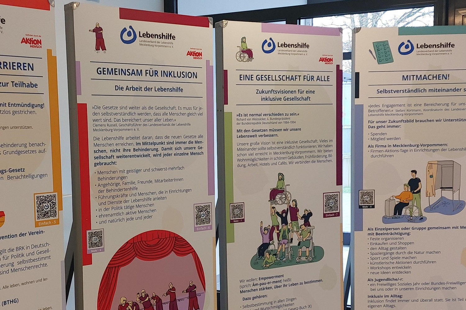 Nebeneinander aufgestellte Roll-up-Banner einer Wanderausstellung der Lebenshilfe Mecklenburg-Vorpommern. Auf den Bannern stehen große Überschriften wie „Gemeinsam für Inklusion“ und „Eine Gesellschaft für alle“, ergänzt durch Informationstexte, QR-Codes 